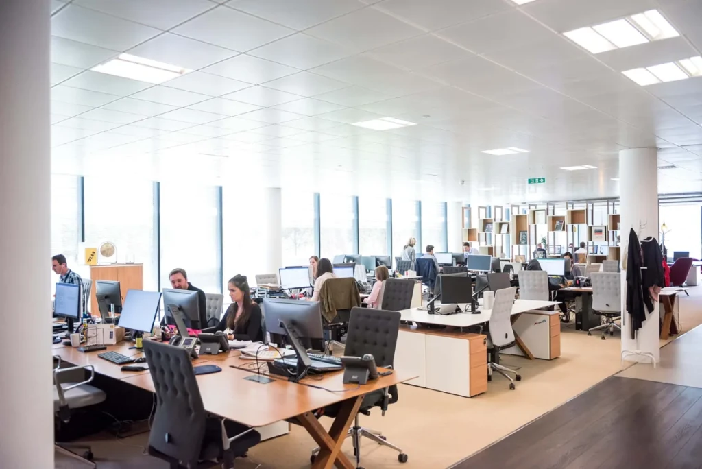 An office with people  working at their desks, focused on their tasks and collaborating with colleagues.